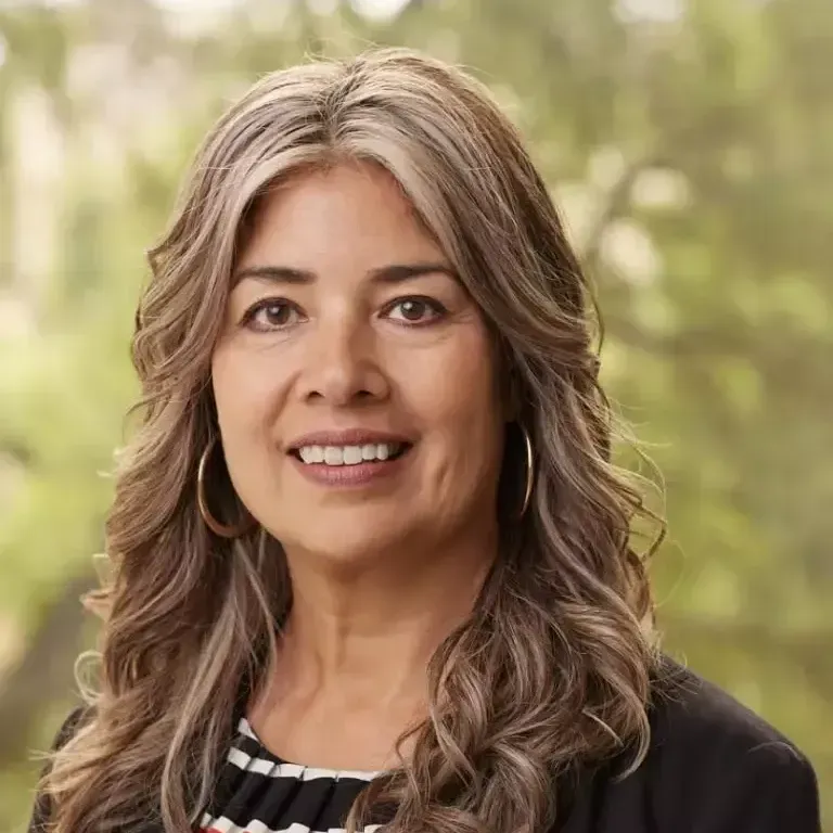 A woman with long hair and earrings is smiling for the camera.