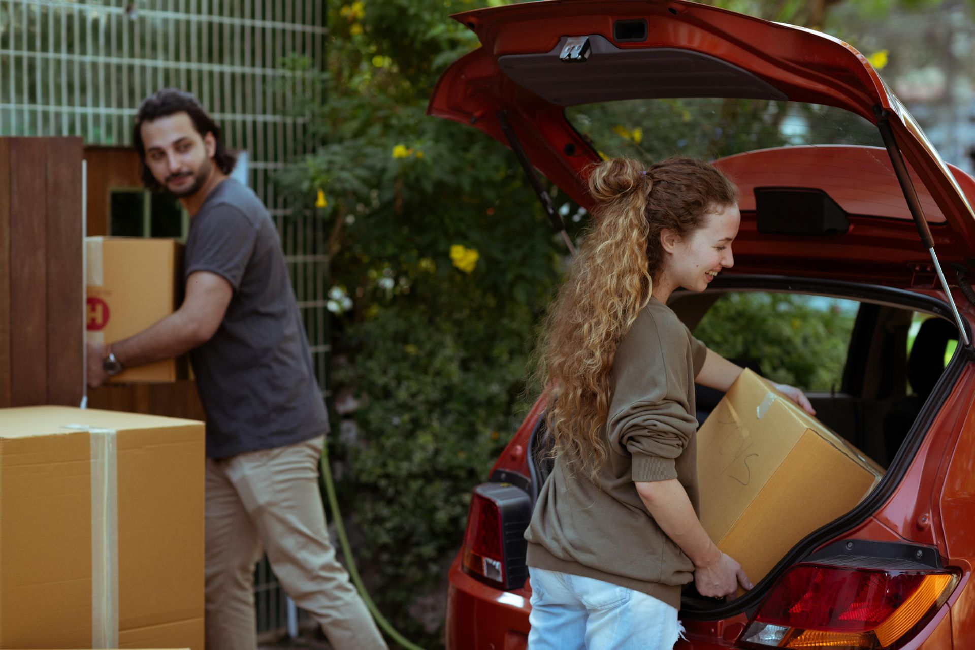 A man and a woman are loading boxes into the back of a car.