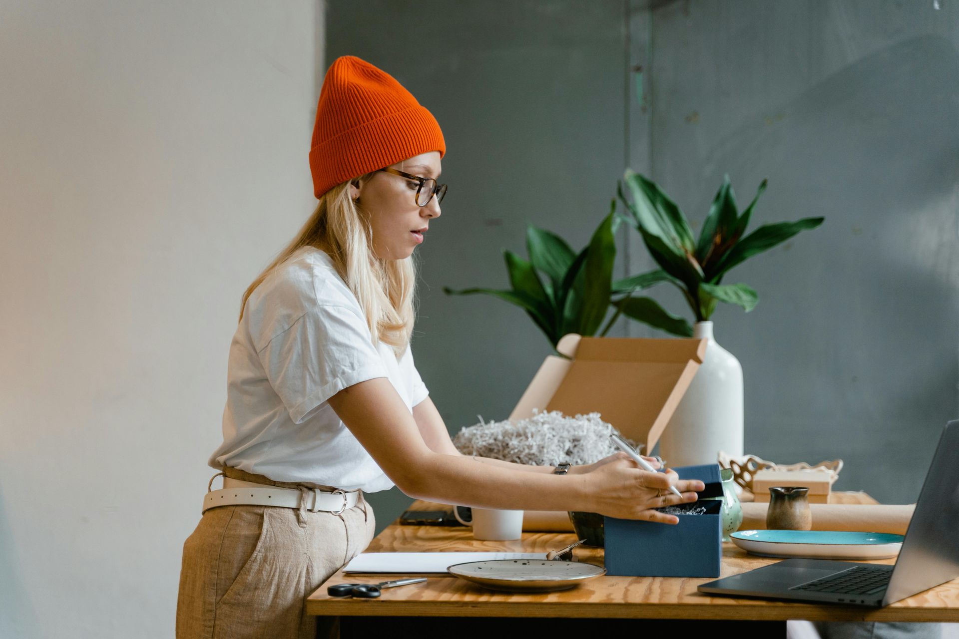 A woman is sitting at a desk packing a box.