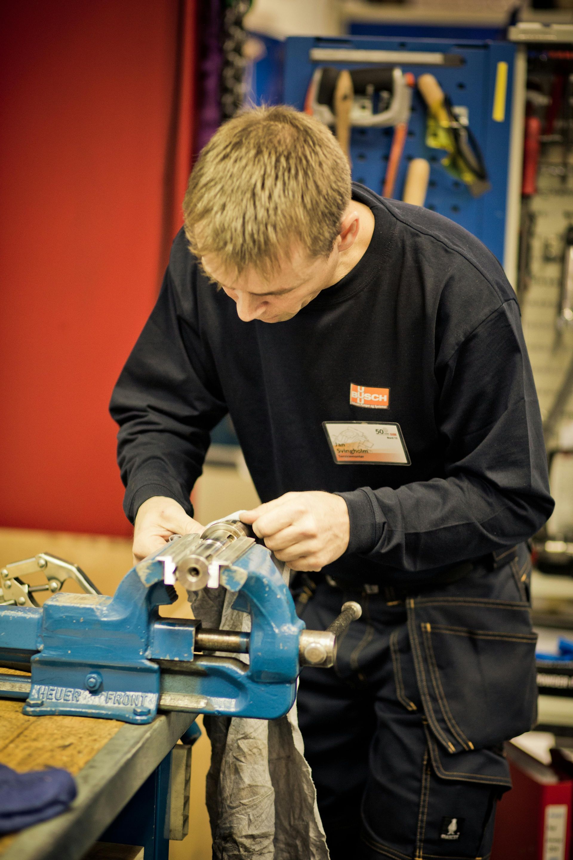 A man is working on a piece of metal with a vise.