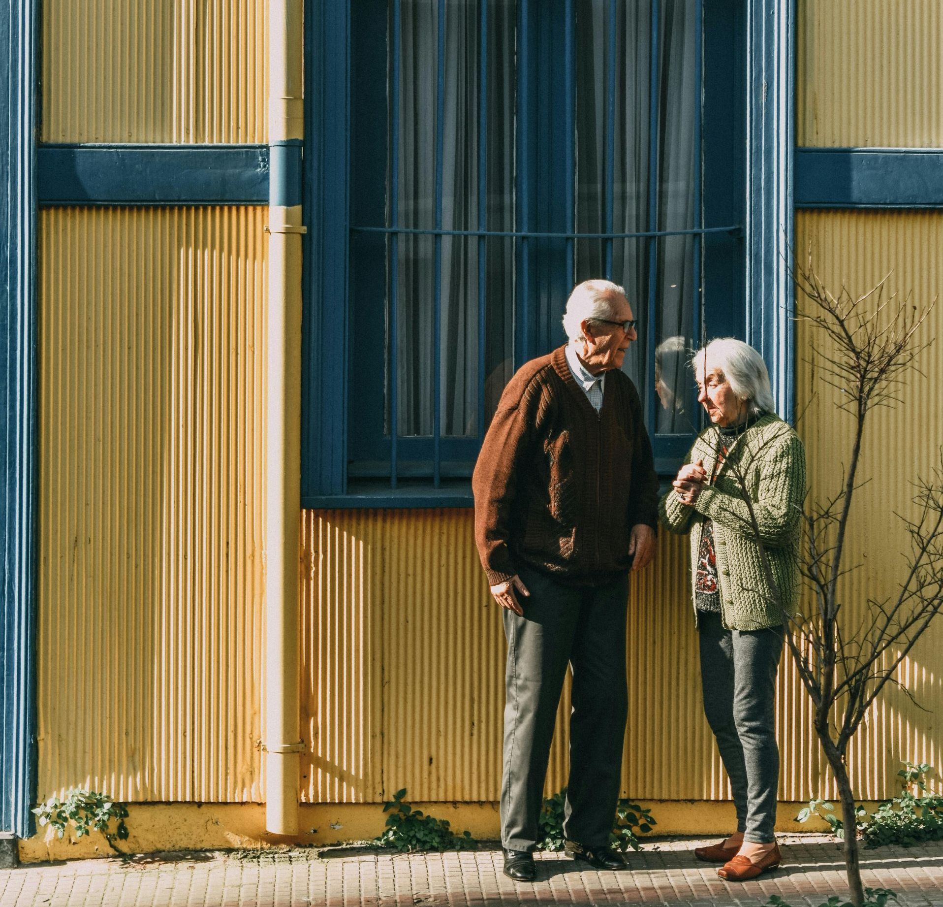 A man and woman standing in front of a yellow building