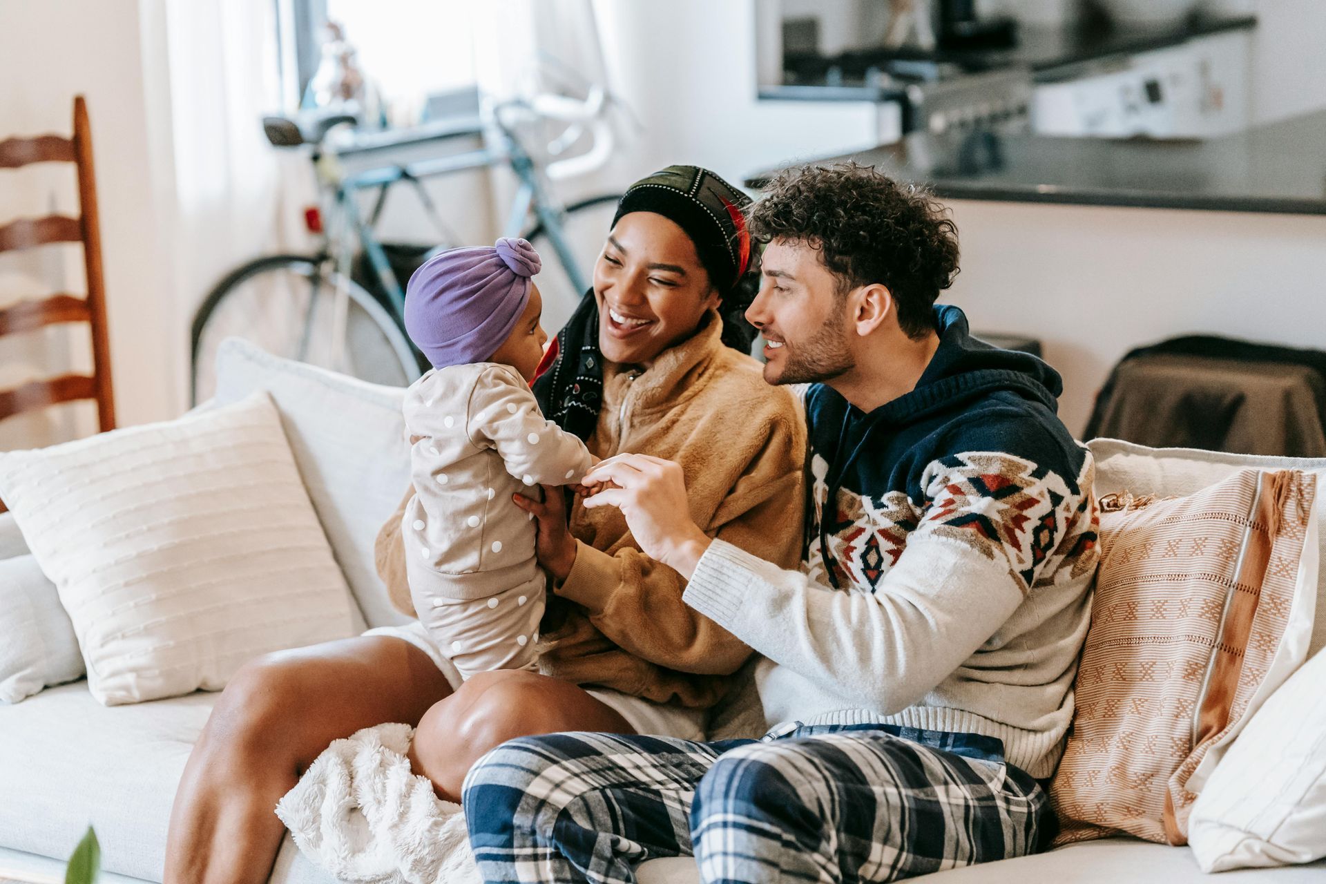 A family is sitting on a couch holding a baby.