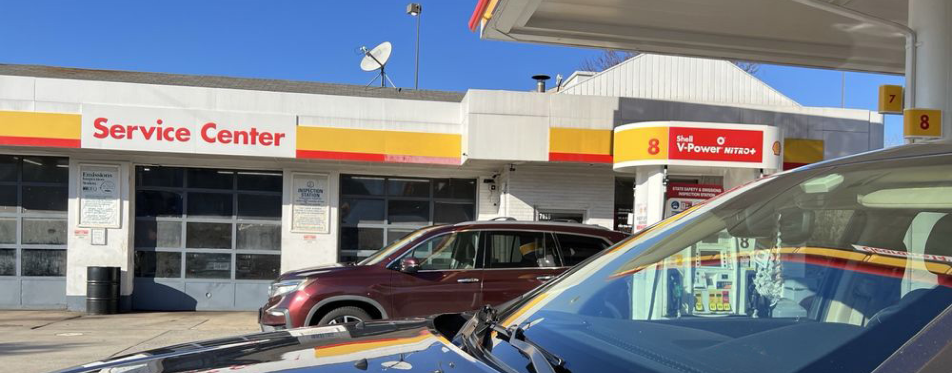 Gas station service center with parked cars under a bright blue sky | Shell Annandale Service