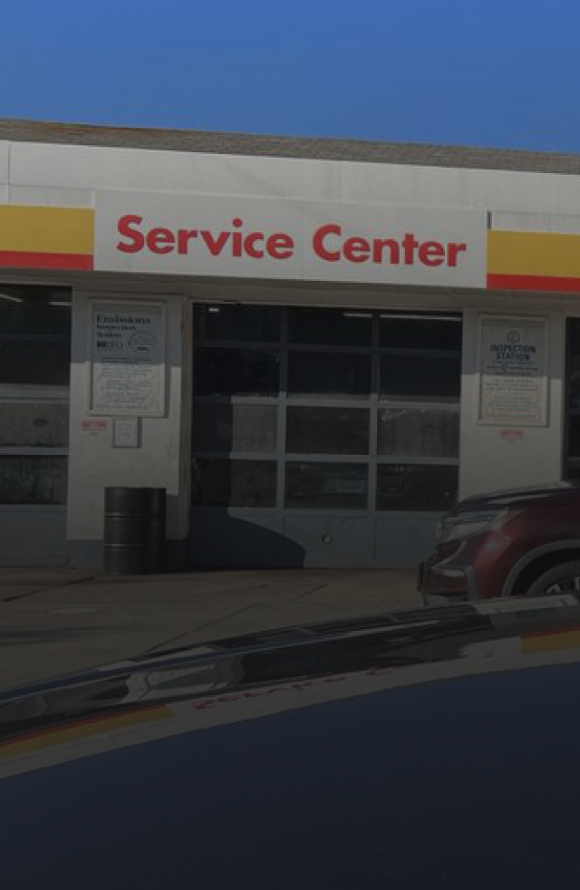 Service Center storefront with red sign and garage doors under a blue sky | Shell Annandale Service