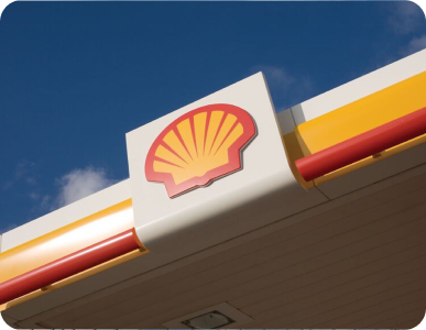 Shell gas station sign on a building, with red and yellow branding against a blue sky | Shell Annandale Service
