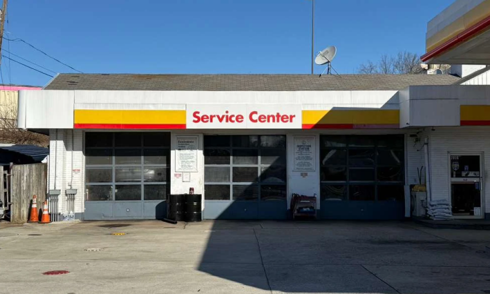 Service Center storefront with white facade, yellow-red sign, and glass doors under a clear blue sky | Shell Annandale Service