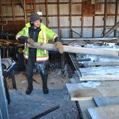 man cutting wood plank in lumber yard