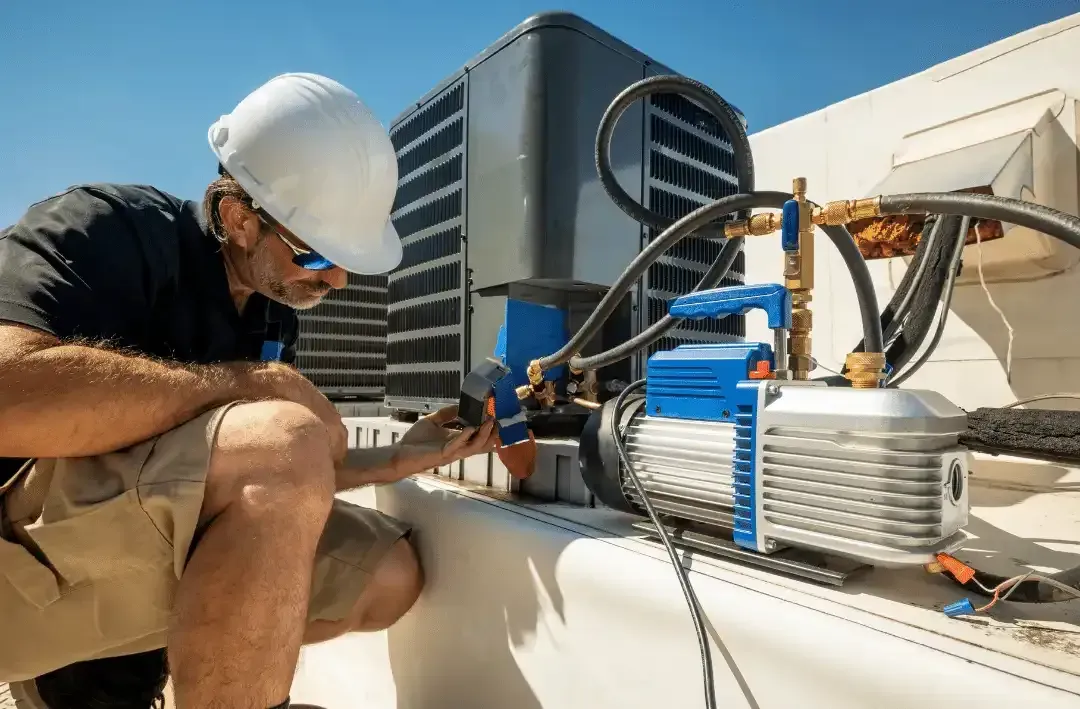 HVAC technician in a white helmet working on rooftop air conditioning unit with blue equipment.
