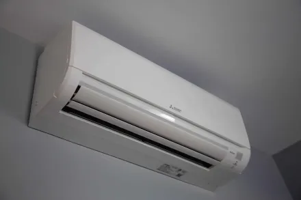 White wall-mounted Mitsubishi air conditioner on a gray wall.