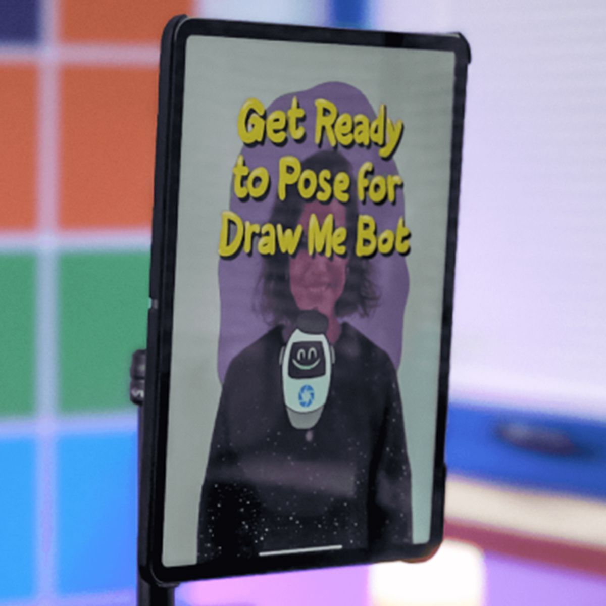 A tablet mounted on a stand displays a person with the text