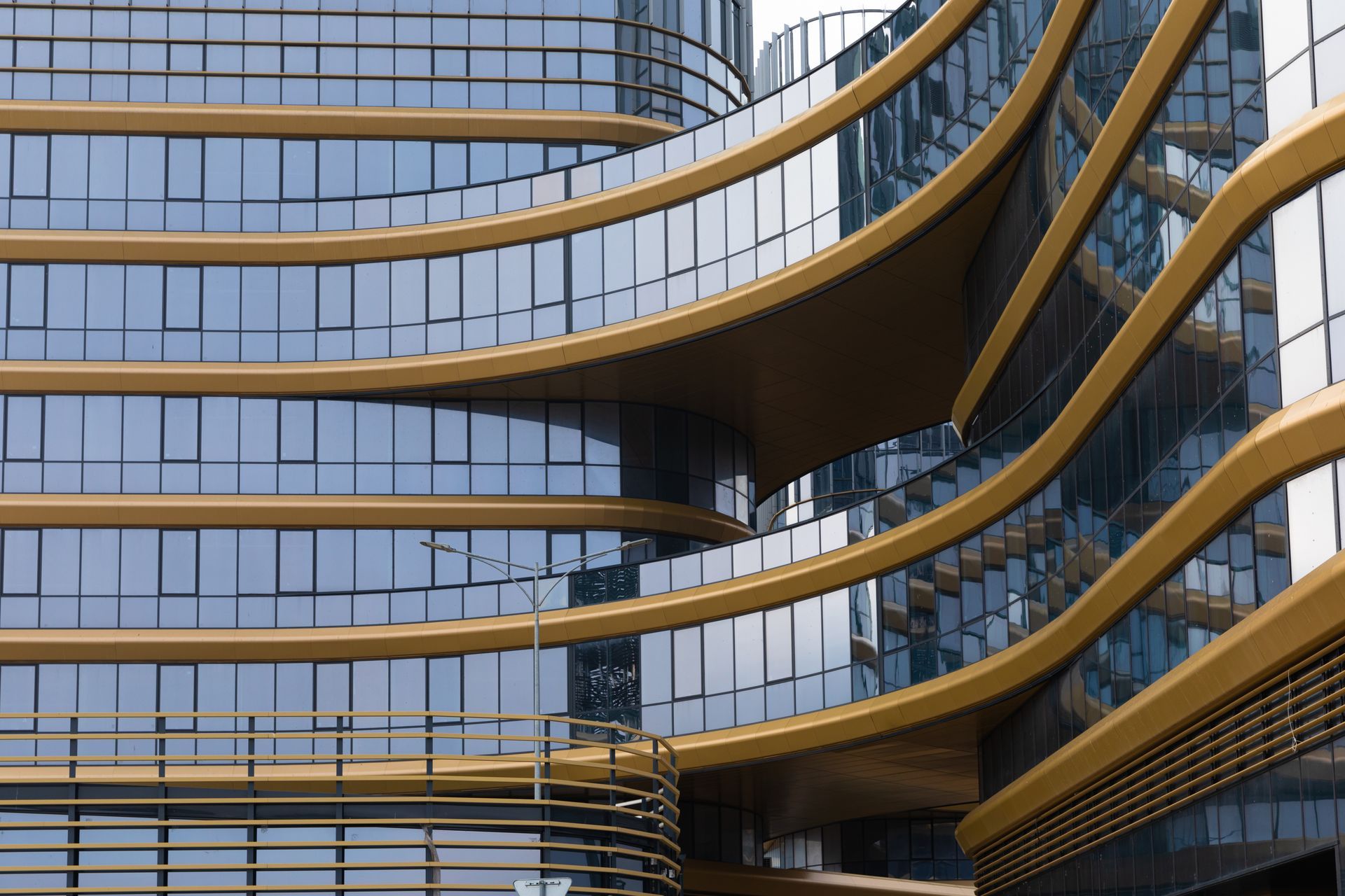 Modern building exterior with curved gold frames and large glass windows reflecting the sky.