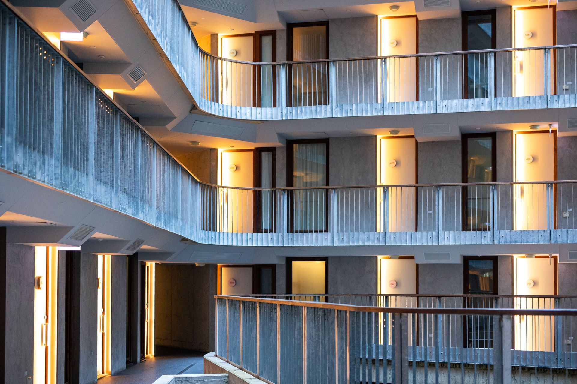 Multi-level building interior with balconies and open doorways, softly lit by interior lights.