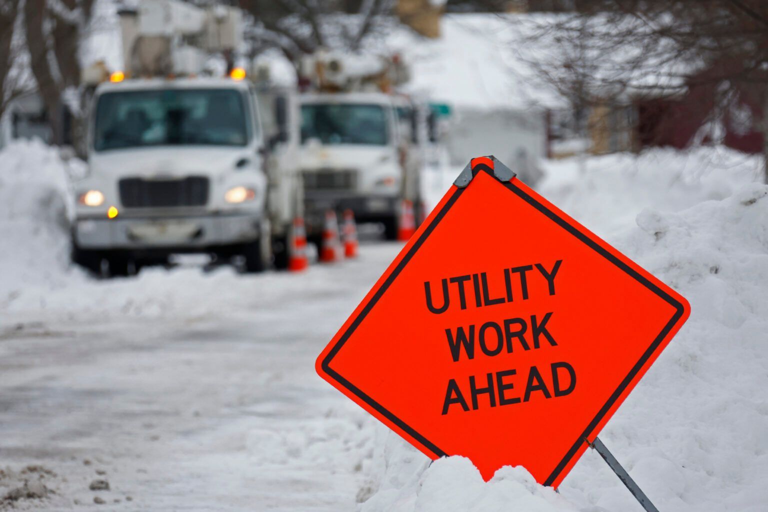 Utility work ahead is written on an orange sign in the snow.