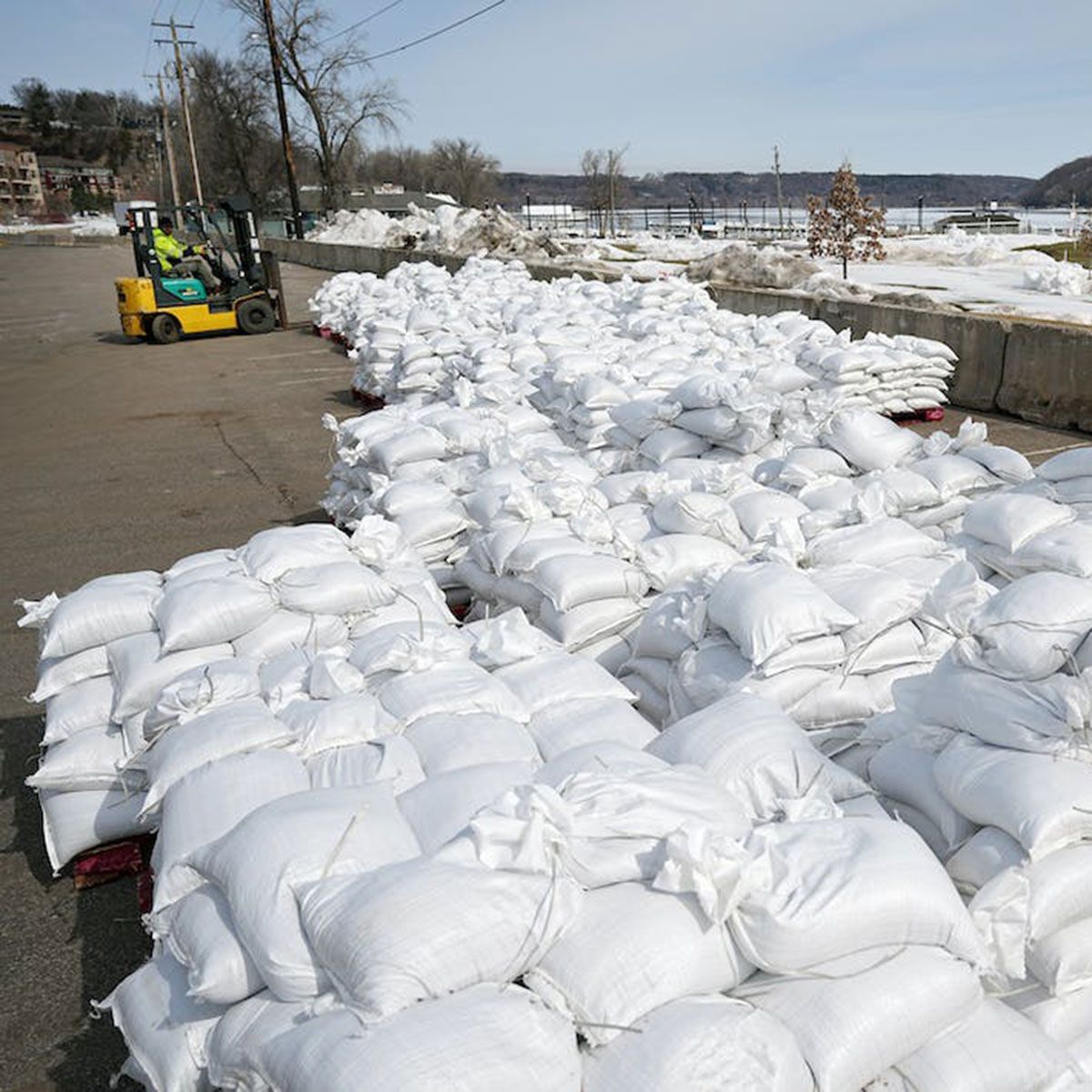 A large pile of white bags with a forklift in the background