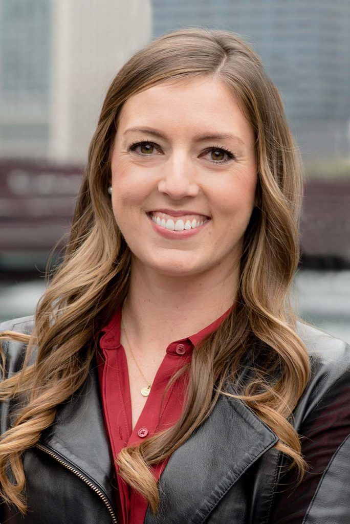 a woman wearing a leather jacket and a red shirt is smiling for the camera .