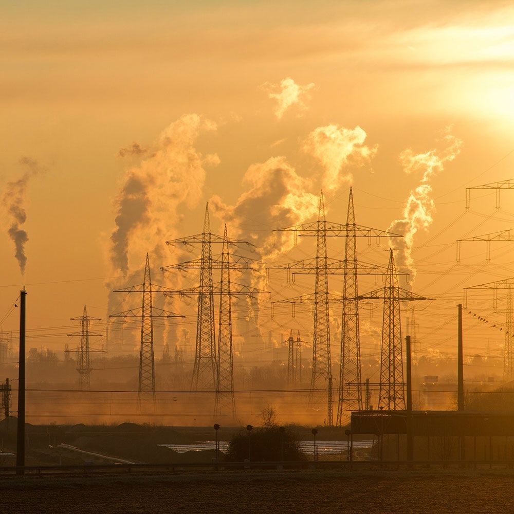 There is a lot of smoke coming out of a factory at sunset.