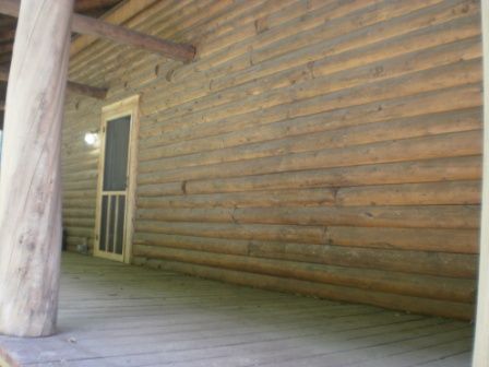 Wooden log cabin exterior with porch and screen door.