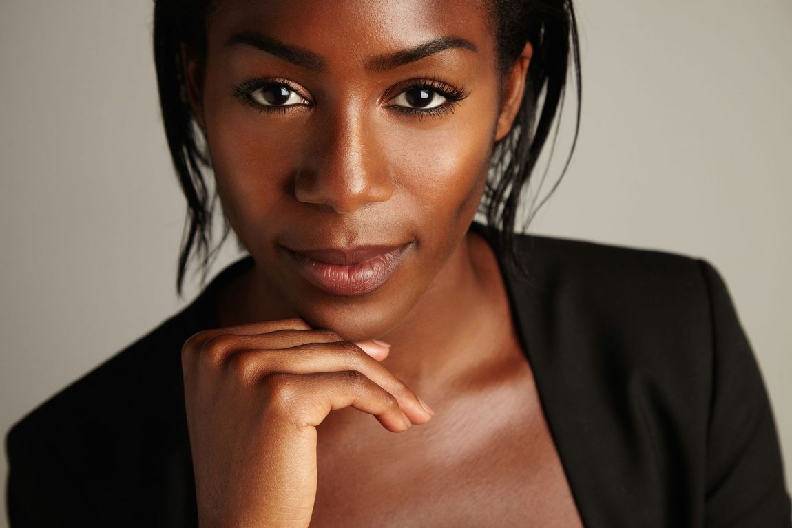 A close up of a woman 's face with her hand on her chin.