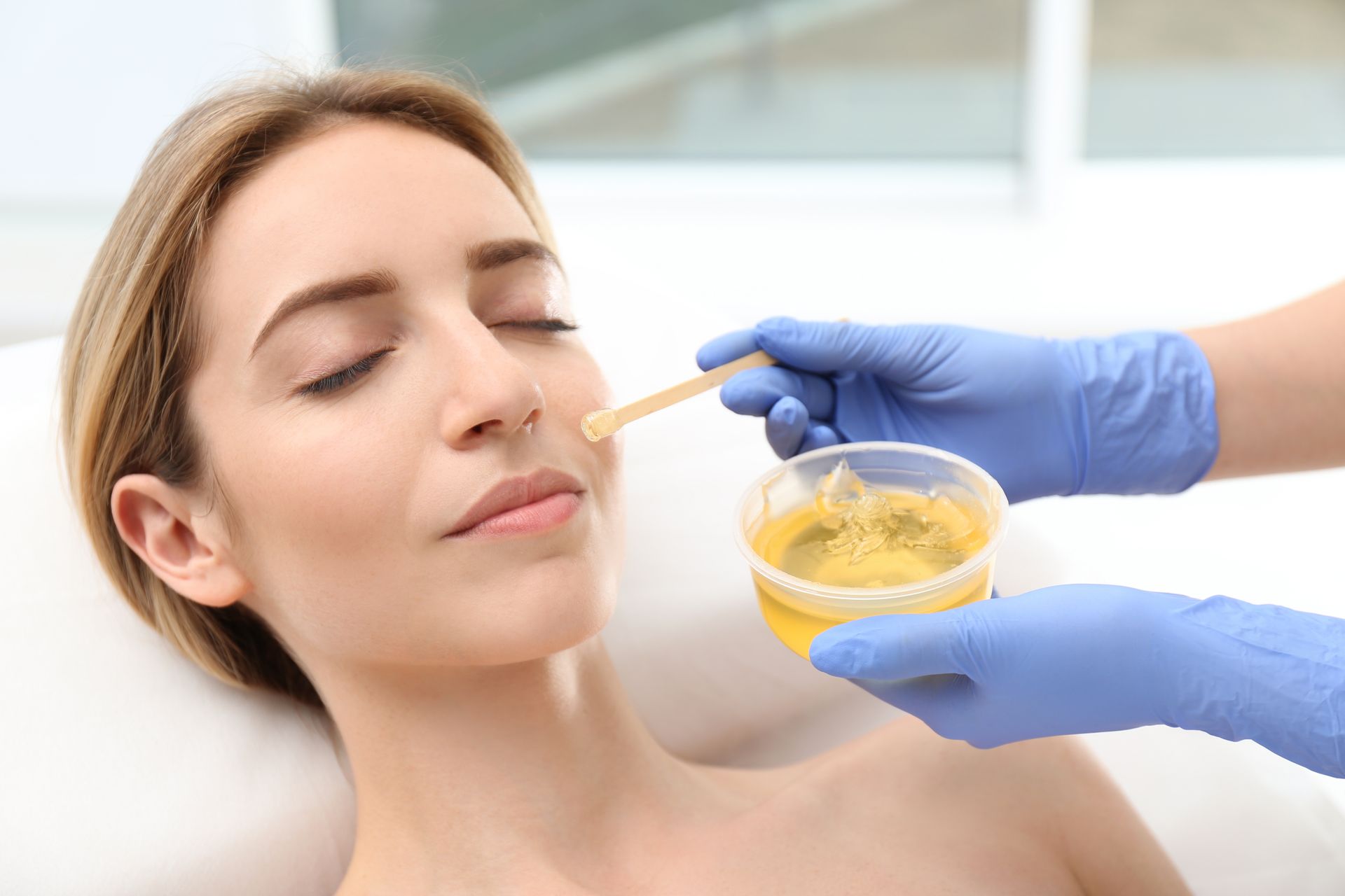 A woman is getting a wax treatment on her face.