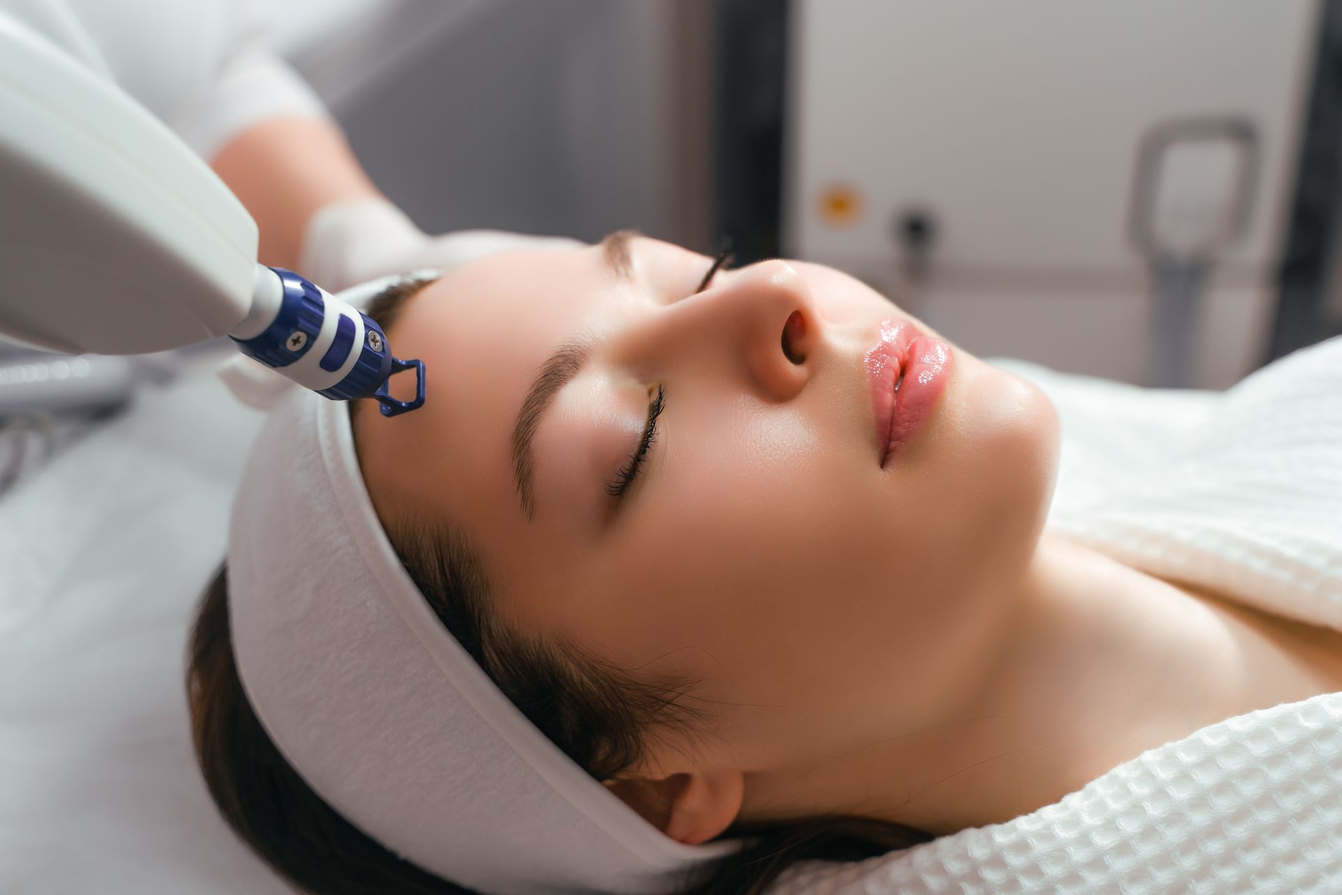 A woman is getting a laser treatment on her face.