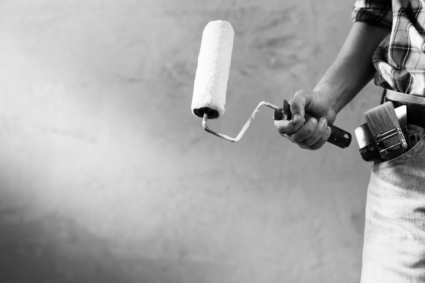 A black and white photo of a person holding a paint roller.