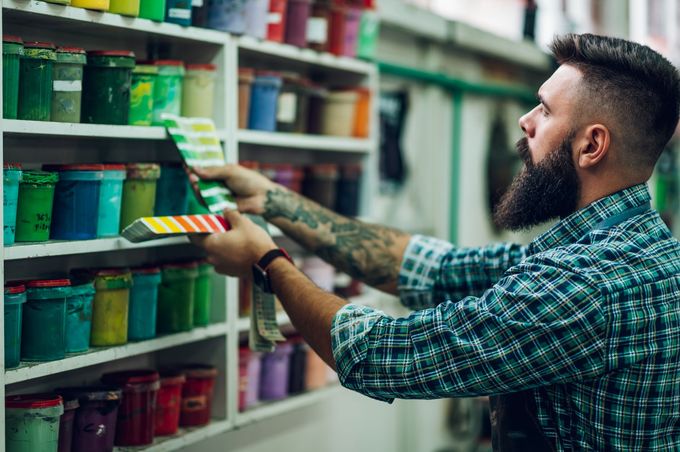 A man with a beard is looking at a color palette in a store.