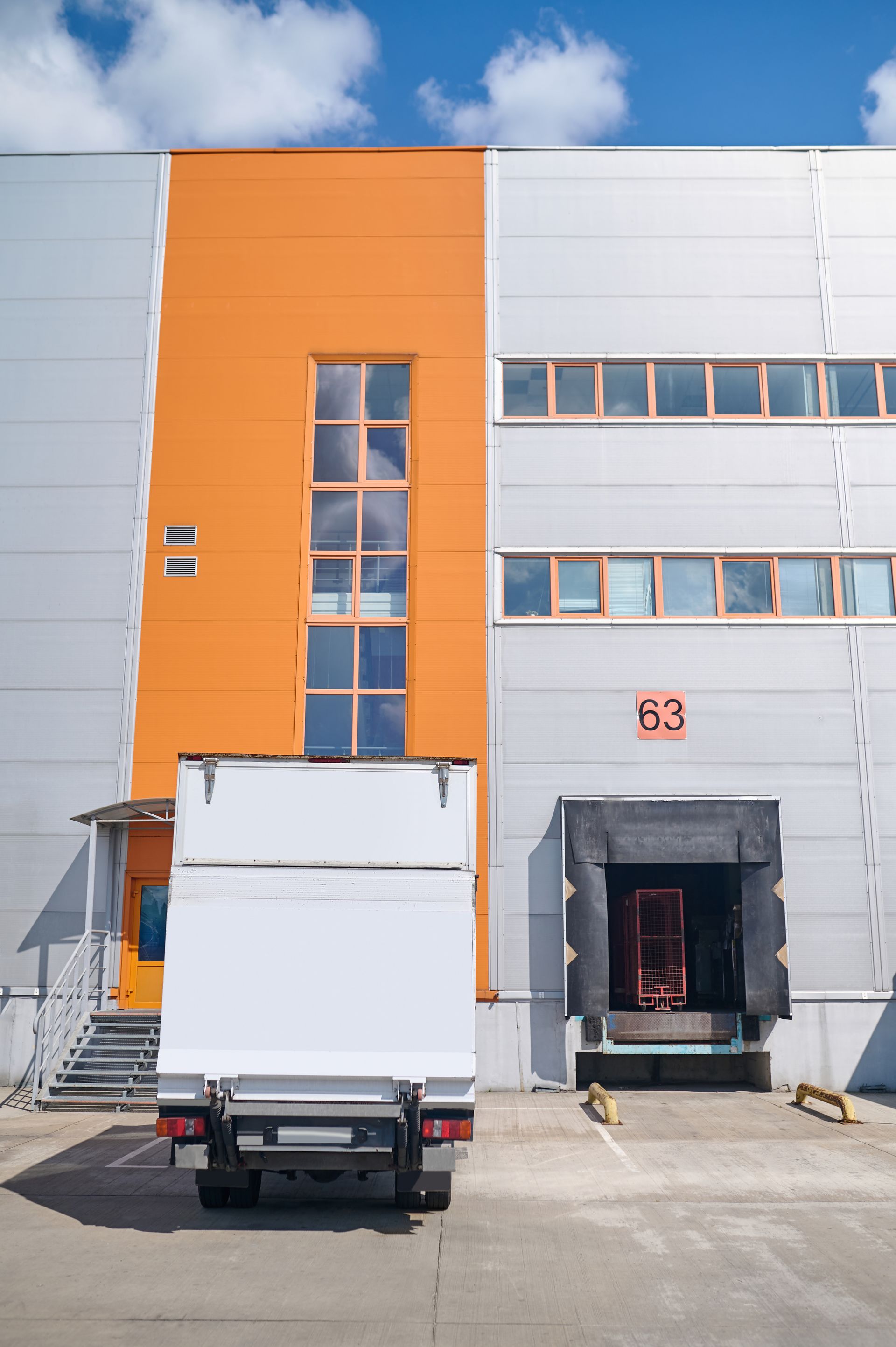 A white truck is parked in front of a large building.