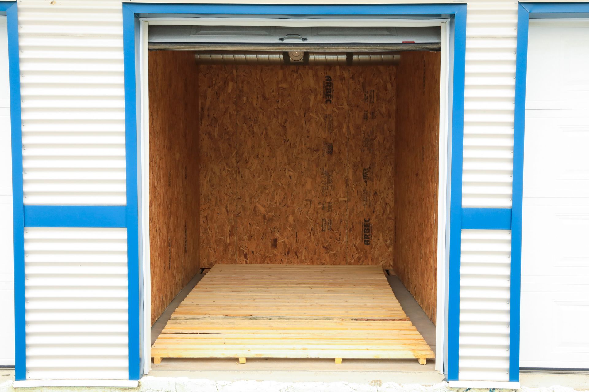 Un garage vide avec un plancher en bois et une porte bleue.