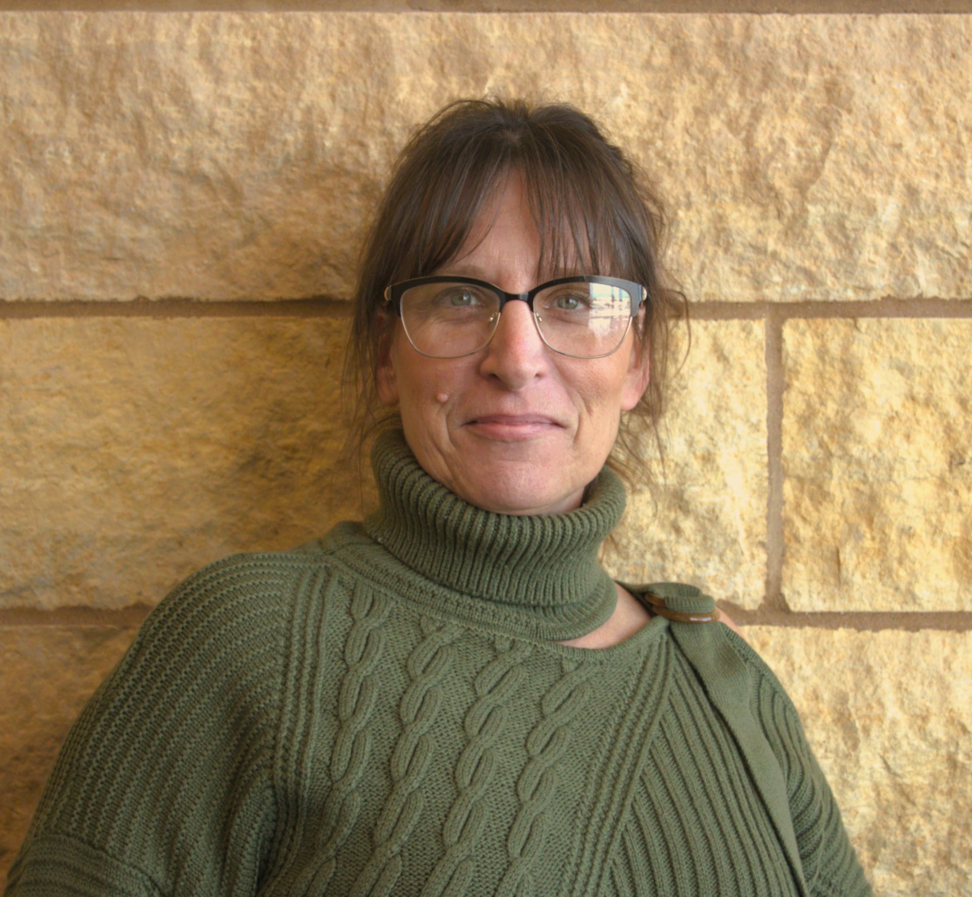 An addiction education counselor in a red sweater is smiling for the camera.