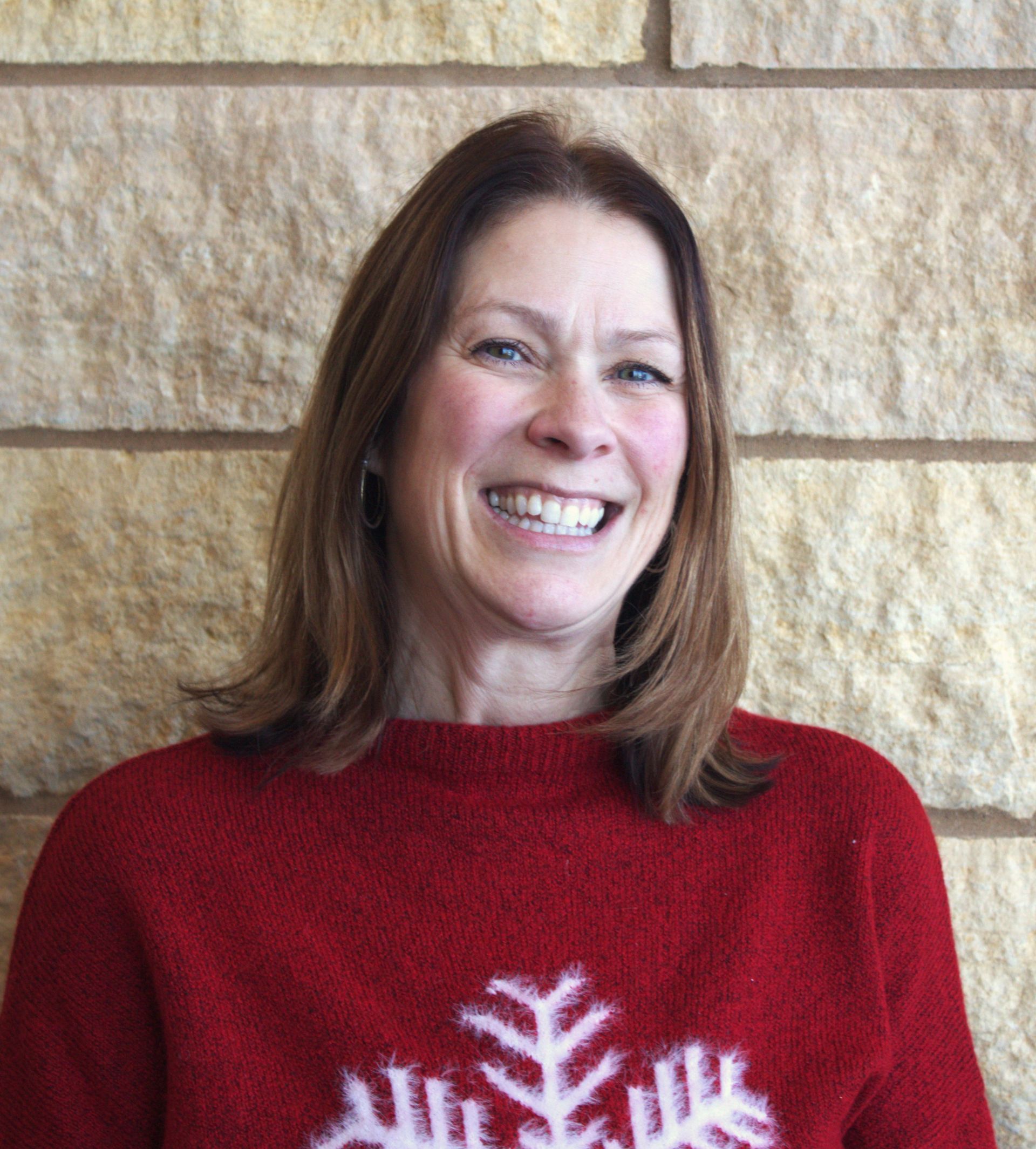 An addiction education counselor with a beard is wearing a plaid shirt and a vest.