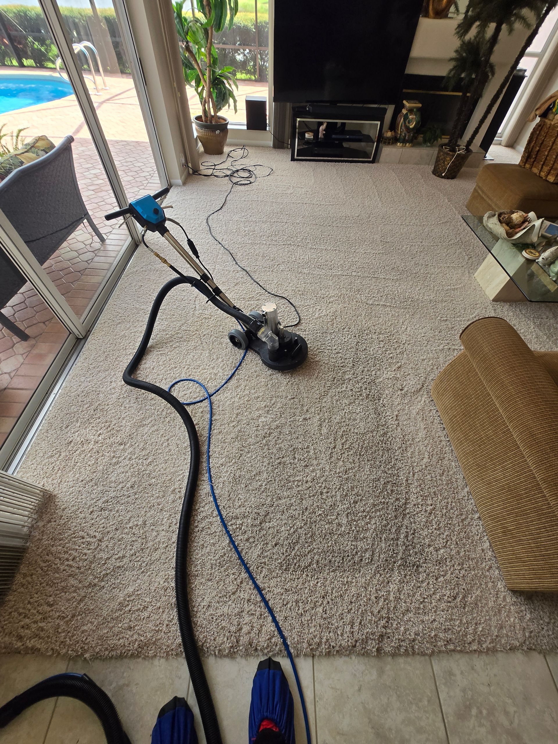 Living room with a vacuum cleaner on a carpet and a TV stand in the background