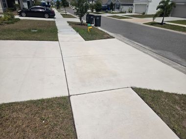 Silver SUV parked on a narrow concrete driveway beside a house and lawn.