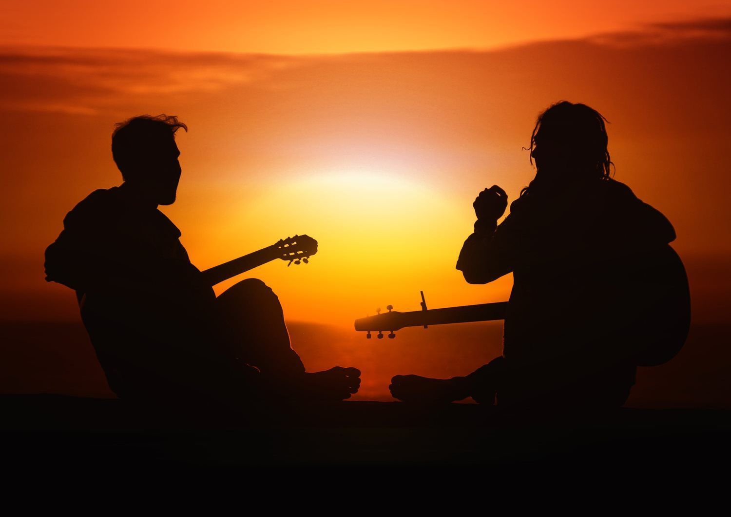 a man and a woman are playing guitars at sunset .