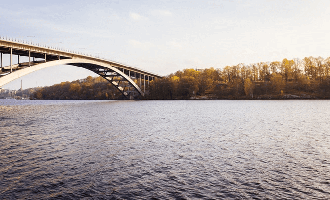 a bridge over a body of water with trees in the background .