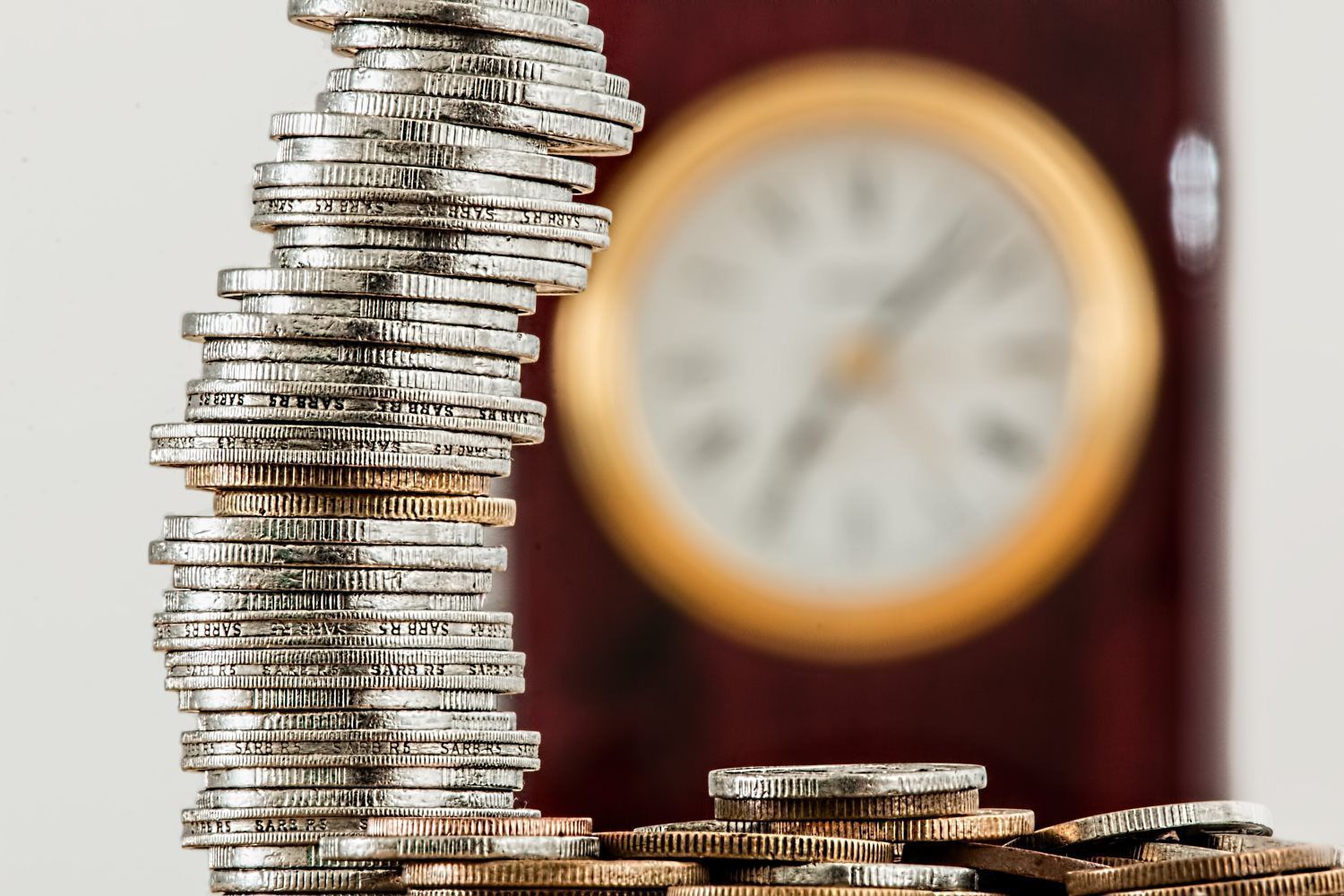 a stack of coins is sitting in front of a clock .