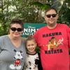 a man wearing a hakuna matata shirt stands next to a woman and a little girl