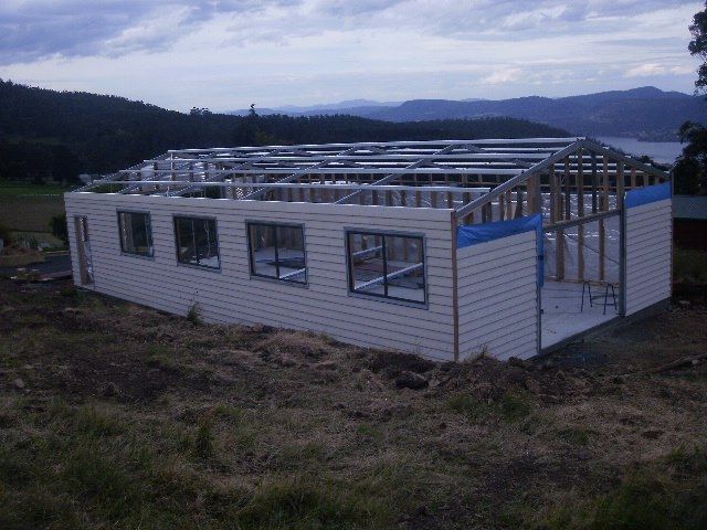 A house is being built in a field with mountains in the background.