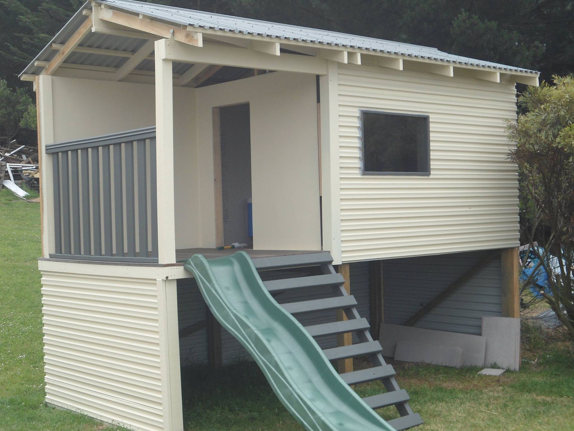 A small house with a green slide and stairs