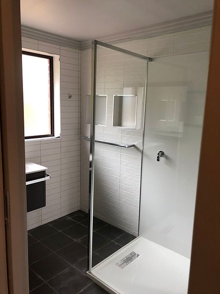 A bathroom with a walk in shower and a window.