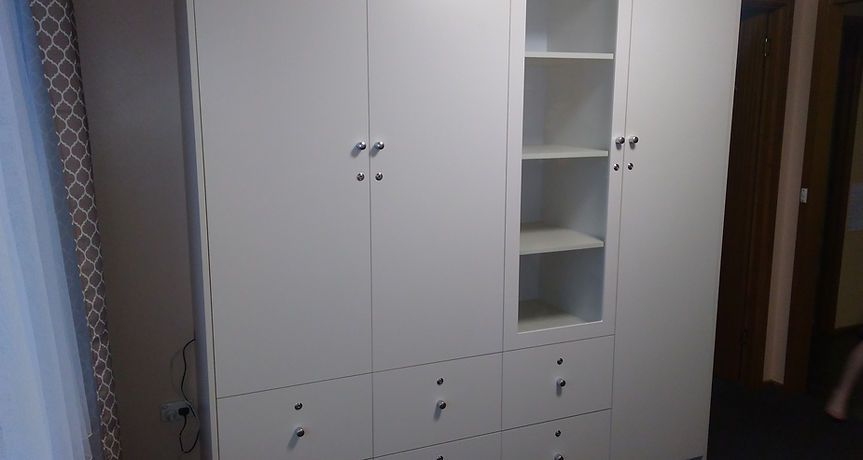 A large white wardrobe with drawers and shelves in a bedroom.