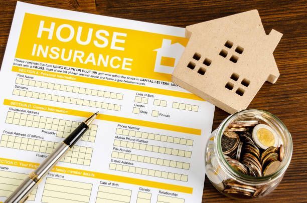 A house insurance form with a pen and a jar of coins on a table.