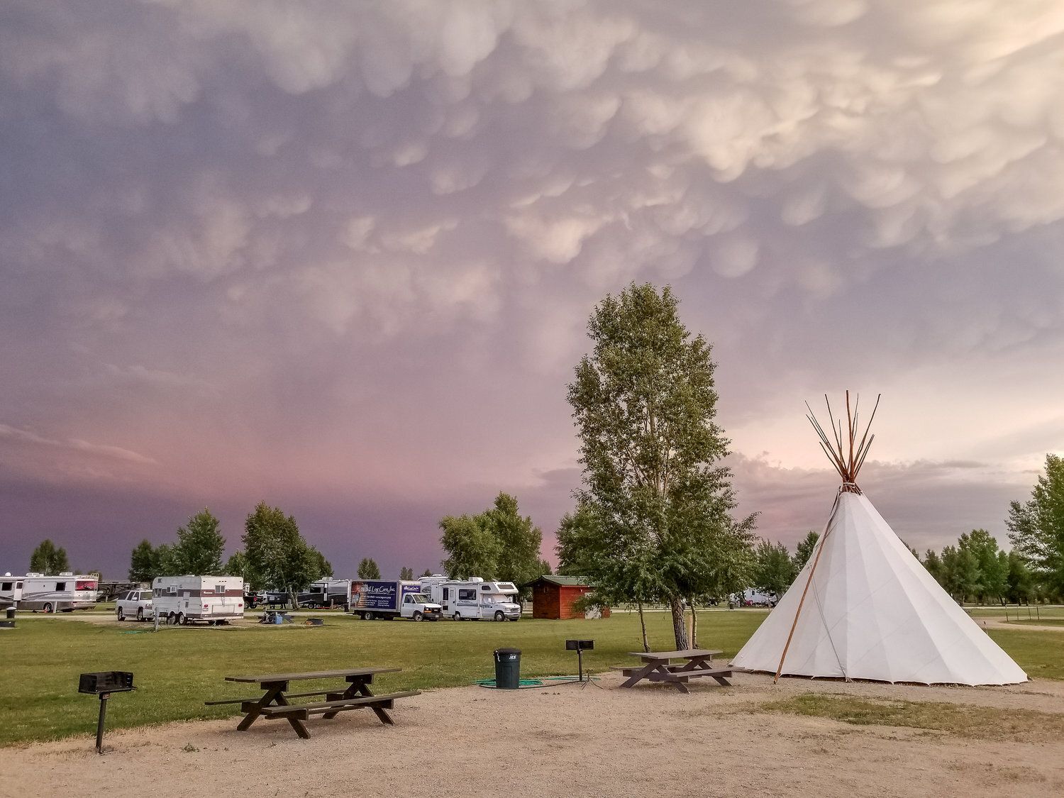 Camping ground with a teepee and RVs under a dramatic cloudy sky.