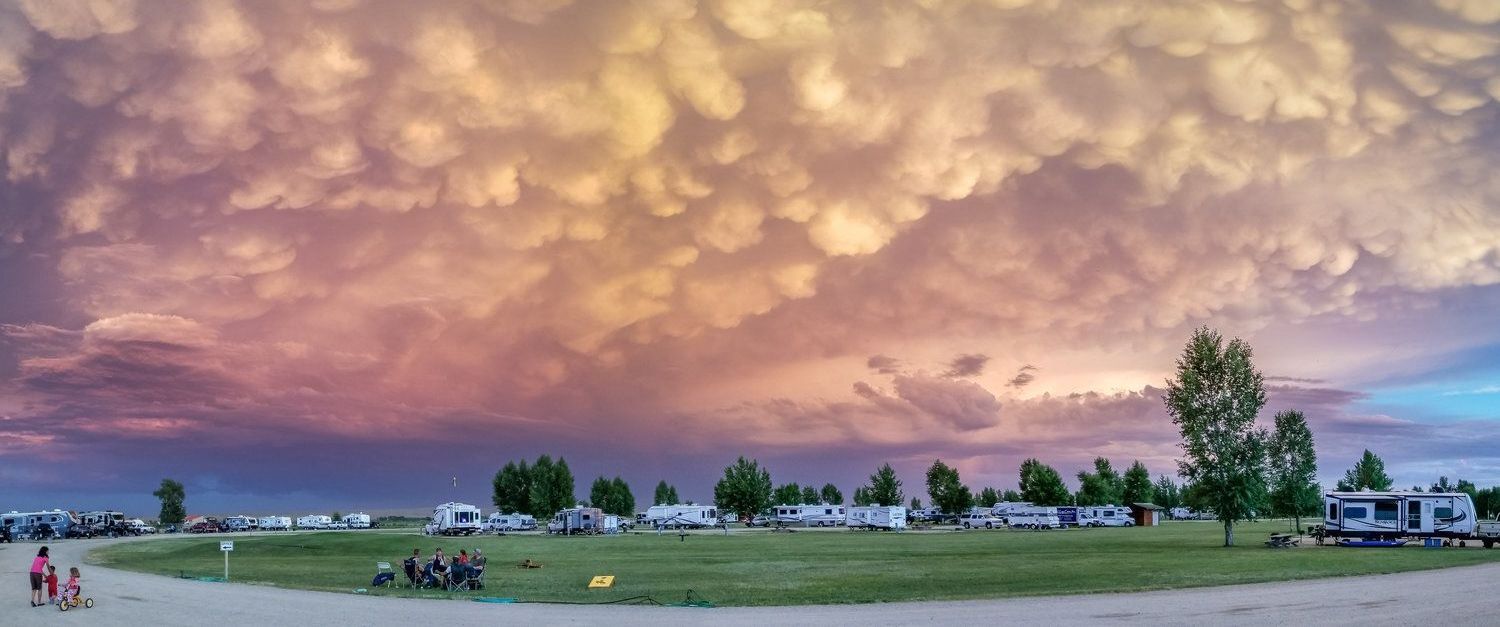 Campground under a dramatic sunset with colorful, textured clouds.