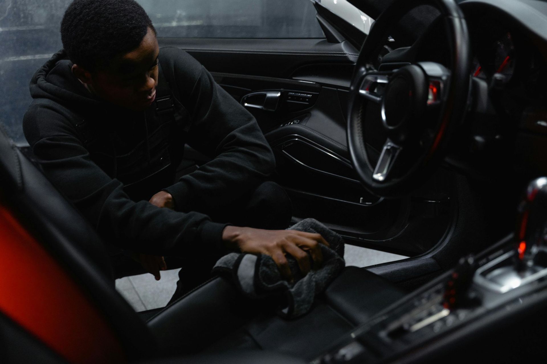 A man is cleaning the interior of a car with a cloth.