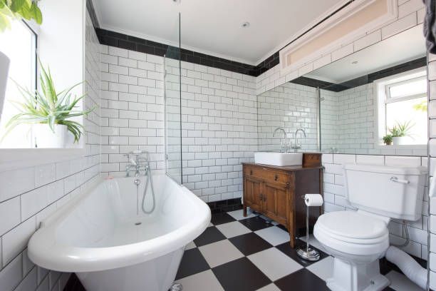 Bathroom with black and white checkered floor, white subway tile walls, clawfoot tub, and antique wooden vanity.