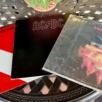 Three vinyl album covers: AC/DC, a black cover, and two others.