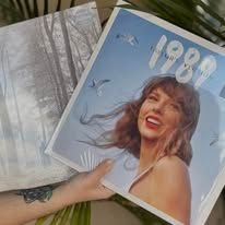Person holding Taylor Swift's "1989" album and a similar album. The "1989" cover is blue.