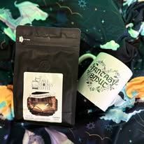 Black coffee bag and white mug with green lettering on a patterned background.