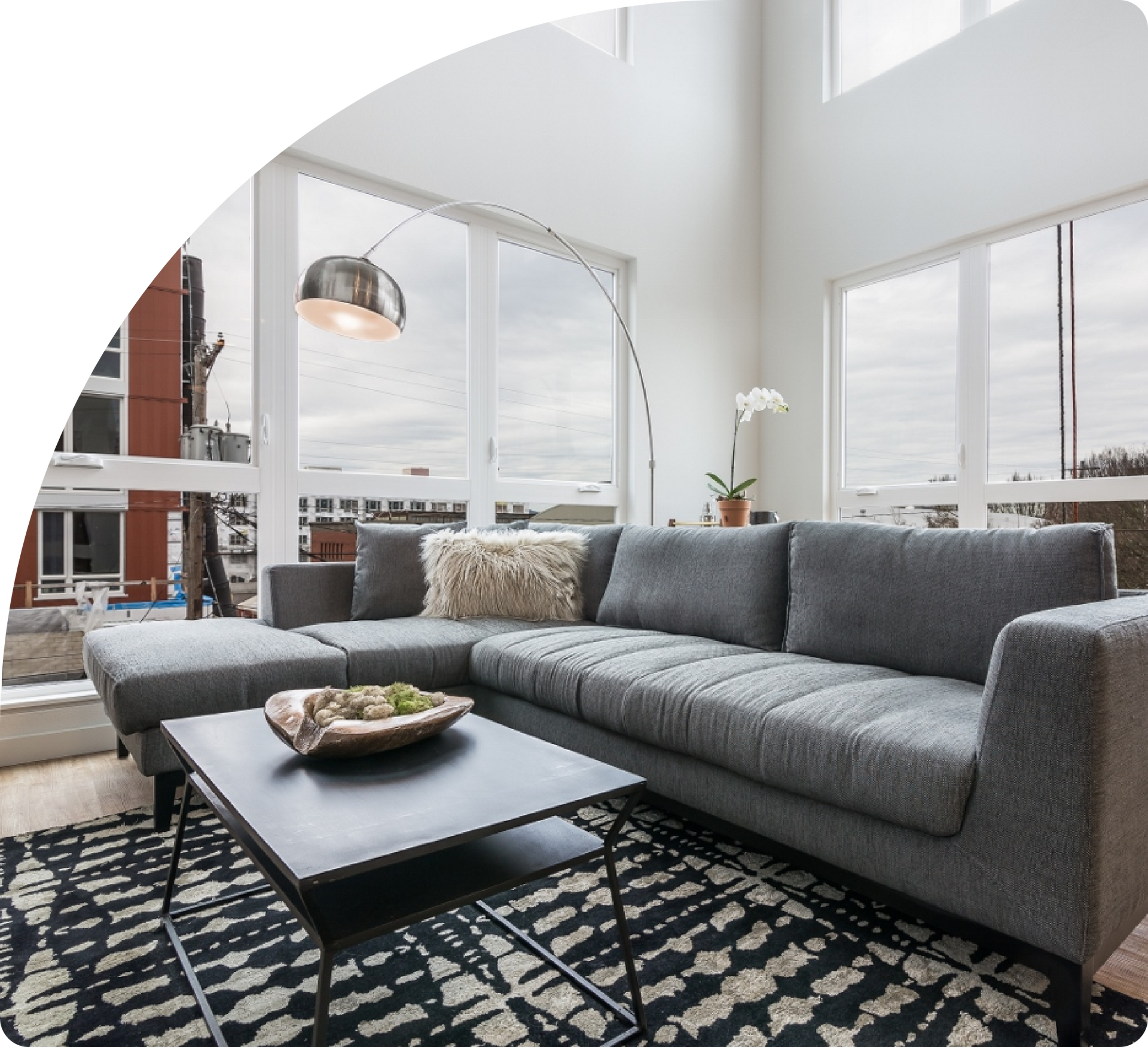Living room with comfy grey couch in front of big windows.