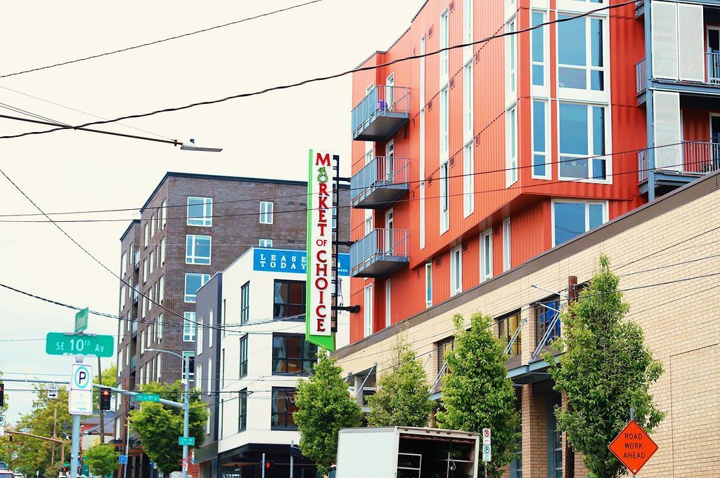 Urban street with modern orange-and-blue buildings and a vertical theater sign, on a cloudy day